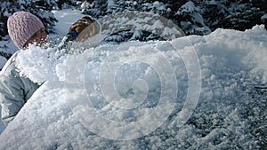 Woman removing snow from a blue Car