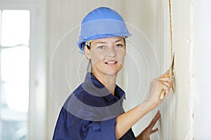 Woman removing wallpaper with scraper