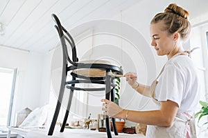 Woman repairing an antique chair in a white studio