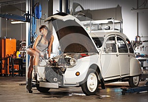 A woman repairing a retro car in a garage