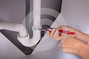 Woman Repairing Sink Pipe With Adjustable Wrench