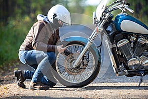 Woman repairing a spoked wheel on a motorcycle on a dirt countryside road