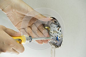 Woman repairs an electric socket with a screwdriver. Installing new socket into the wall. Installation wire into a plug. Holding