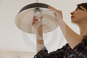 Woman replacing light bulb at home. Power save LED lamp changing