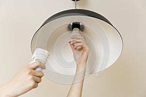 Woman replacing light bulb at home. Power save LED lamp changing photo