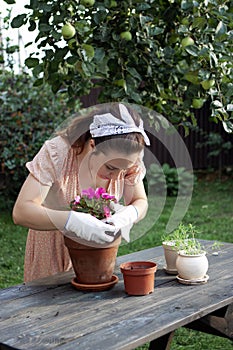 A woman replants an impatiens in a new pot