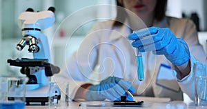 Woman researcher in gloves examines test tube with liquid