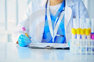 Woman researcher is surrounded by medical vials and flasks, isolated on white background