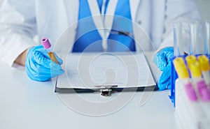 Woman researcher is surrounded by medical vials and flasks,  on white background