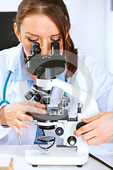 Woman researcher using microscope in laboratory.