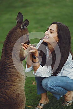 Woman in the reserve is playing with a kangaroo