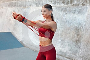 Woman. Resistance Band Workout At Outdoor Stadium For Strong Muscular Body. Fitness Girl In Fashion Sportswear.