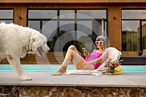 Woman rest with her dog near house with a swimming pool