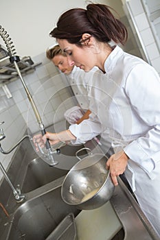 Woman in restaurant kitchen washing dishes photo