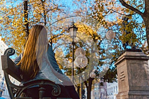 Woman resting on bench after stroll in fall city