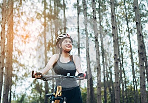 Woman resting with bicycle in the forest after ride workout