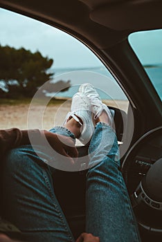 woman resting in car parked at sea beach