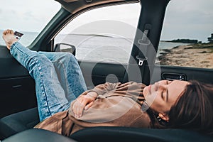 woman resting in car parked at sea beach