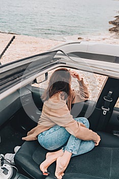 woman resting in car parked at sea beach