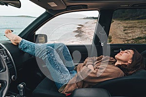 woman resting in car parked at sea beach