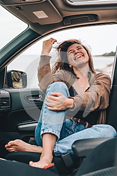 woman resting in car parked at sea beach