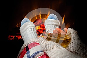 Woman resting with cup of tea near fireplace