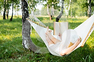 Woman resting in hammock outdoors. Relax and reading the book.