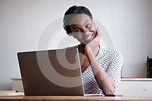 Woman resting head on hand sitting at desk with laptop