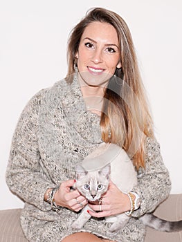 Woman resting in house sofa with kitten cat siamese in home couch