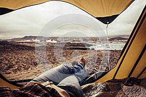 Woman resting inside a tent with beautiful landscape outdoor - travel amd wanderlust alternative lifestyle concept for people love