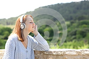 Woman resting listening to music in a balcony