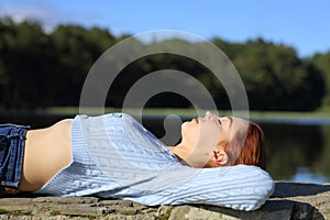 Woman resting lying beside a lake in the mountain