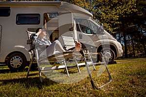 Woman resting near motorhomes in nature. Family vacation travel, holiday trip in motorhome RV, Caravan car Vacation.