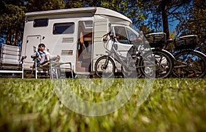 Woman resting near motorhomes in nature. Family vacation travel, holiday trip in motorhome RV, Caravan car Vacation.