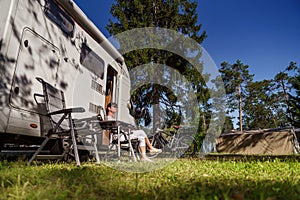 Woman resting near motorhomes in nature. Family vacation travel, holiday trip in motorhome RV, Caravan car Vacation.