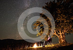 Woman resting at night camping in mountains under starry sky