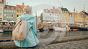 Woman resting on the shore of the Nyhavn canal in Copenhagen