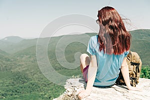 Woman resting on top of rock high in mountains.