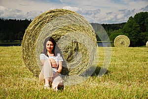 Woman resting under a straw bale