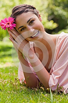 Woman restling her head against her arms while holding a flower