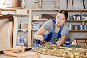 Woman restorer restores wooden frame surface of vintage mirror in workshop