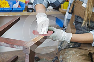 woman restoring furniture using sand paper