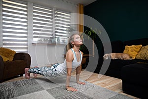 The woman rests her toes on the floor and her hands and bends her body. Fitness at home.
