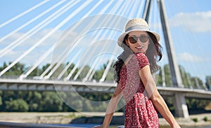 WOMAN rests on the river in the city. Background bridge