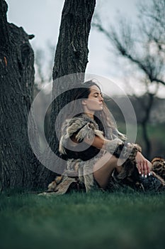 Woman rests under tree on grass in image of warrior amazon