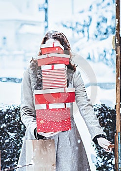 woman returning home from shopping holding pile of christmas present boxes