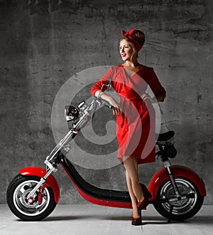 Woman ride sit on motorcycle bicycle scooter pinup retro style laughing smiling red dress