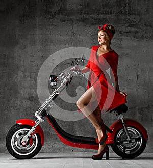 Woman ride sit on motorcycle bicycle scooter pinup retro style laughing smiling red dress