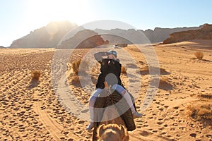 Woman rides a camel and tries to take photos in desert