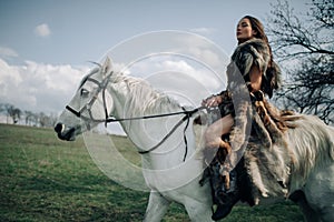 Woman rides on horseback in field in image of warrior amazon